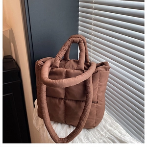 Detail of brown quilted nylon tote bag featuring fluffy diamond stitching and dual straps