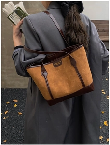 Detail view of a dual-tone tan tote bag with cat embossed logo on a shoulder-worn model