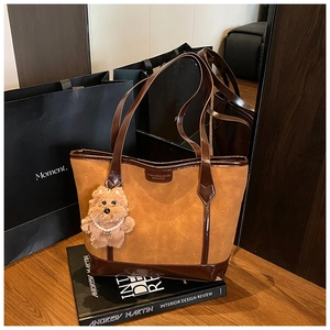 Detail of brown textured tote bag with embossed pattern and cute plush dog charm