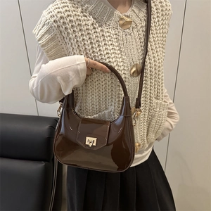 Brown patent leather crescent shoulder bag with metallic clasp and adjustable strap