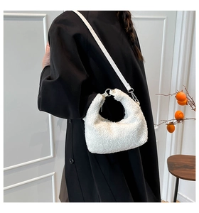 Detail of white faux shearling crescent bag with silver hardware and adjustable strap