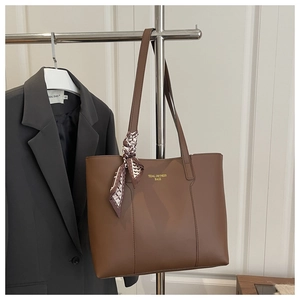 Détail d'un sac cabas marron avec foulard en soie et logo doré tidal dryness