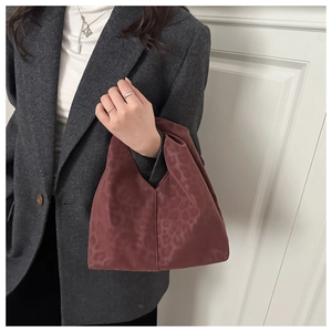 Détail du sac à main bordeaux à motif léopard avec texture douce et design plissé