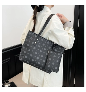 Detail of black clover print tote bag and detachable mini pouch on a female model