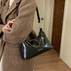 Détail du sac hobo noir brillant avec bandoulière chaîne argentée et lettrage mode