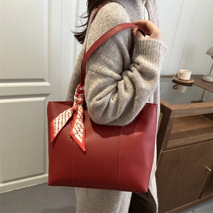 Chic red leather tote bag with a decorative geometric scarf on the handle for women