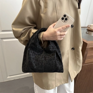Schicke schwarze Handtasche mit Leopardenmuster aus Textil, getragen zum Trenchcoat