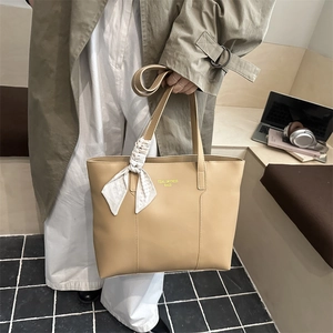 Grand sac cabas kaki avec détail de foulard présenté dans un décor de style de vie décontracté