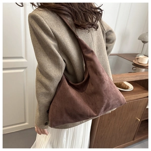 Detail of dark brown suede hobo bag featuring wide shoulder strap and spacious design