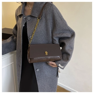 Nahaufnahme einer braunen Lederhandtasche mit goldenem Drehverschluss am Mantel