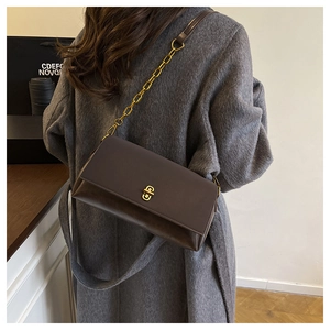 Detail der dunkelbraunen Lederhandtasche mit goldenem Drehverschluss und Kettenriemen