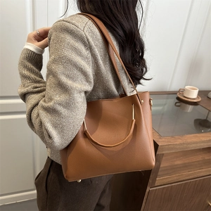 Brown litchi grain leather tote bag with metal ring handle shown in a daily setting