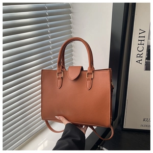 Detail of a brown lychee pattern leather tote with matte gold hardware and dual handles