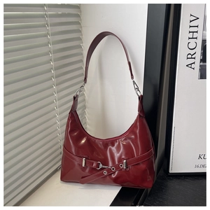 Detail of burgundy patent leather hobo bag with silver buckle and glossy finish