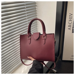 Close-up of burgundy tote bag with pebble leather texture and gold metal ring hardware