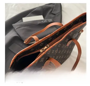 Detail view of large tote bag with brown monogram pattern and smooth golden metal zipper
