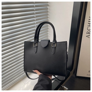 Detail of black tote bag with lychee grain leather, gold hardware and detachable strap