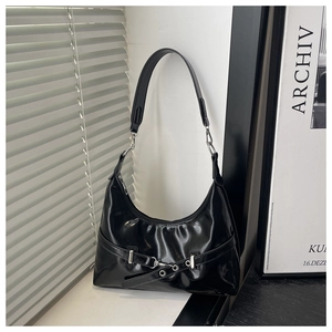 Close-up of black glossy patent leather shoulder bag with metallic buckle detail