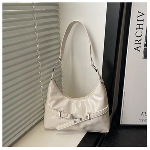 Detail of cream underarm bag with silver hardware and pleated texture in soft window light