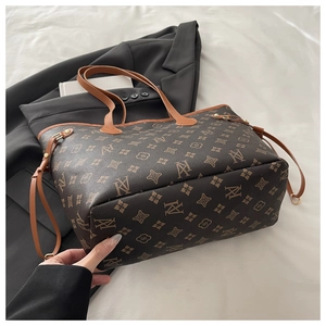 Detail view of large brown monogram tote bag with adjustable side drawstrings and contrast handles