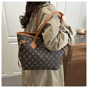 Detail of monogram pattern and adjustable side straps on a brown leather tote bag