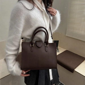 Elegant retro brown leather handbag with adjustable strap shown in a lifestyle street shot