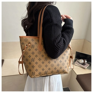 Detail of retro monogram tote bag with brown leather straps and adjustable side laces