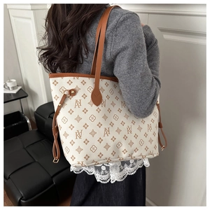 Detail view of large ivory monogram tote bag with brown leather trim and side drawstring
