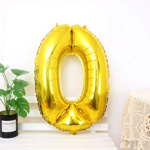 Detail of a shiny gold number 0 foil balloon on a white bench in a bright party setting