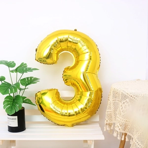 Detailed close-up of a 32-inch gold number 3 foil balloon on a white wooden bench