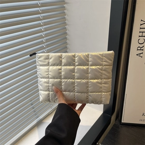 Silver quilted cosmetic bag with metallic finish held by hand, modern minimalist style