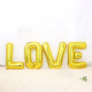 Detail of gold LOVE foil balloons with pink hearts on a white plush carpet decor