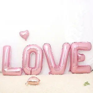Pink metallic foil LOVE letter balloons with heart accents on a white plush rug