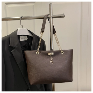 Détail du sac cabas en cuir marron foncé avec pendentif cerf doré et bandoulière