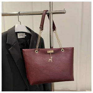 Détail du sac cabas bordeaux avec pendentif cerf doré et bandoulière en chaîne