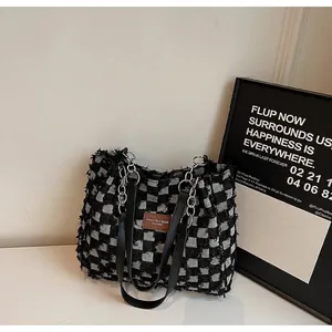 Modern black and white checkered tweed tote bag with leather chain strap and fringe trim