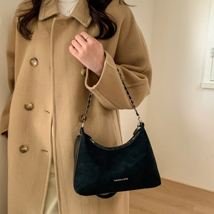 Détail du sac demi-lune noir avec bandoulière chaîne sur un manteau en laine