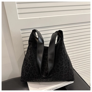 Chic leopard print tote bag with black leather handles displayed on a modern black stool