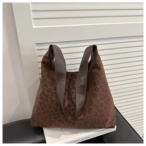 Detailed close-up of leopard print tote bag with brown leather handles and plush texture