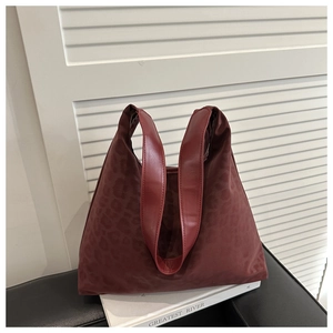 Detail of red-brown tote bag with leopard texture and smooth leather handles