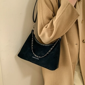 Sac hobo croissant en daim noir avec chaîne argentée porté par un mannequin