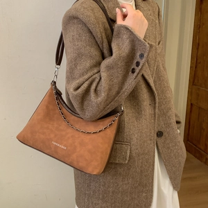 Détail du sac demi-lune marron avec chaîne argentée et texture cuir mat