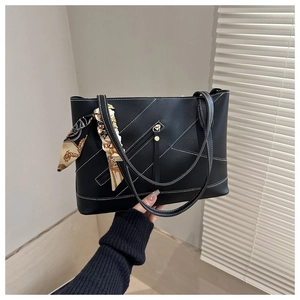 Detailed view of black PU leather tote with contrast stitching and silk scarf accessory