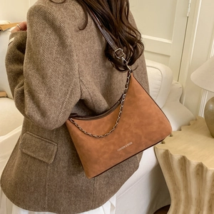 Détail du sac bandoulière demi-lune en daim marron avec chaîne et logo gravé