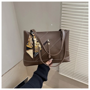 Detail of dark brown tote bag featuring contrast stitching and a decorative silk scarf handle