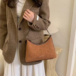 Détail d'un sac hobo marron rétro avec bandoulière chaîne et lettrage stylisé