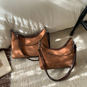 Gros plan de deux sacs hobo en daim marron foncé avec chaîne en métal et bandoulière