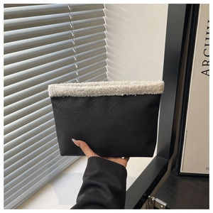 Vista dettagliata della borsa tote in pelle nera con bordo in sherpa bianco e texture