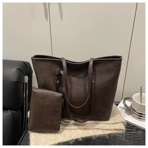 Detalle del bolso tote marrón oscuro con textura de cuero granulado y remaches dorados