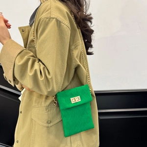 Green plush crossbody phone bag with quilted texture and gold chain strap on model